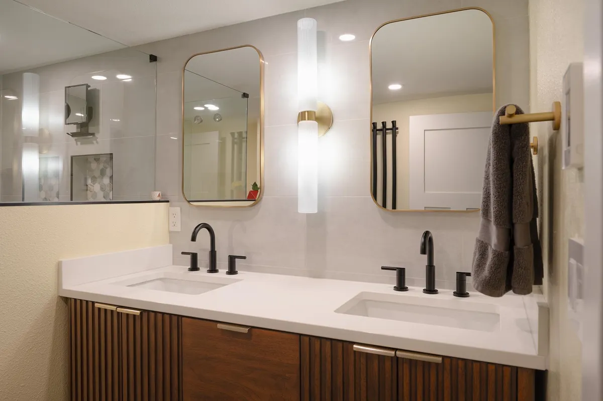 Fluted walnut double vanity with brass sconces and rounded mirrors