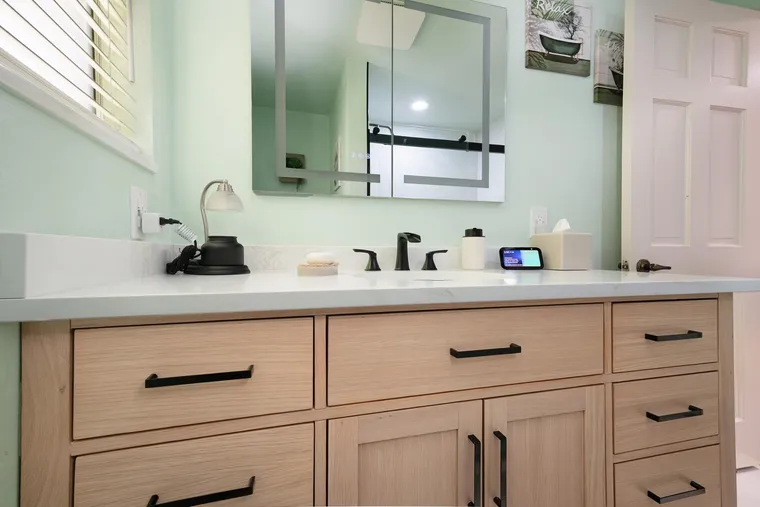 Light oak vanity with black pulls and a white counter