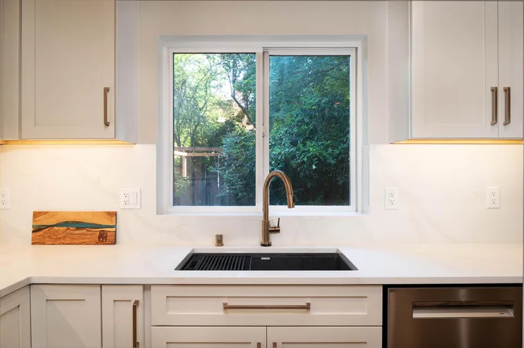 White cabinets and a marble-look backsplash around a sink window