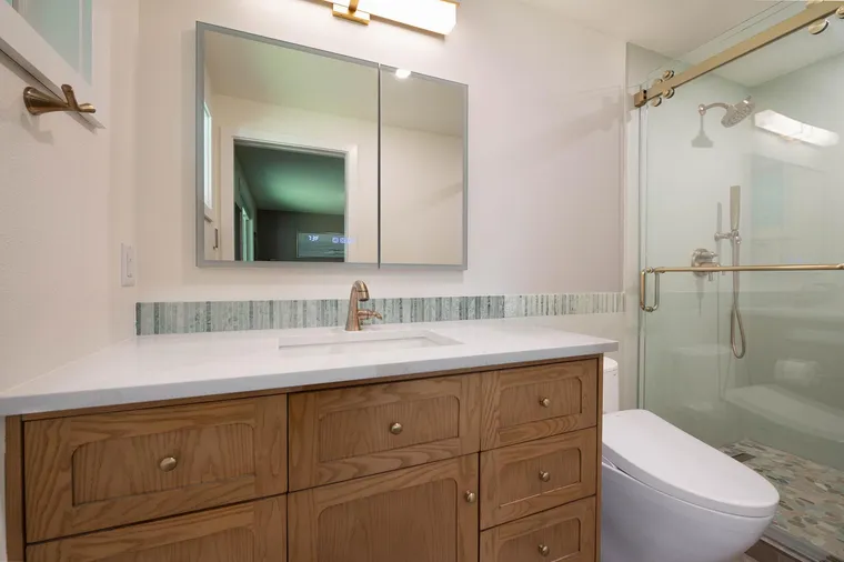 Oak vanity, brass light and a glass shower