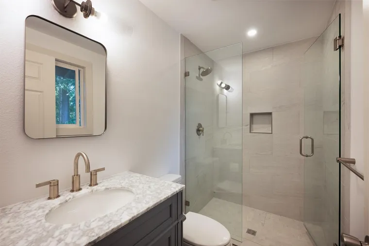 Marble-top vanity next to a frameless glass shower