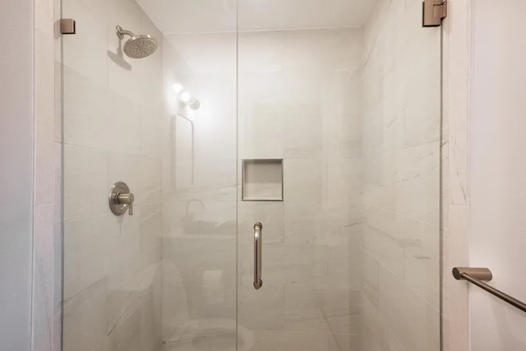 Frameless glass shower with brushed nickel fixtures