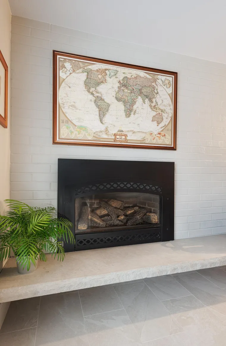 Fireplace with a white surround and a framed map above