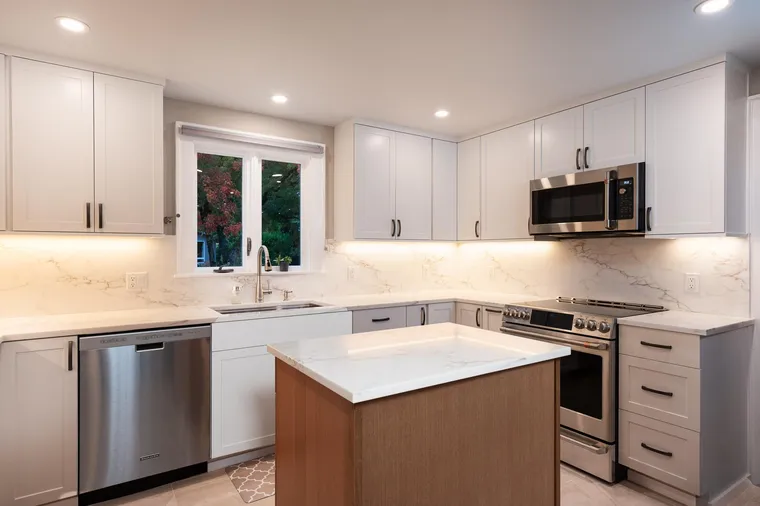 White kitchen with a small wood island and stainless appliances