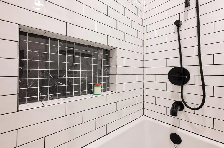 Long shower niche lined in black tile