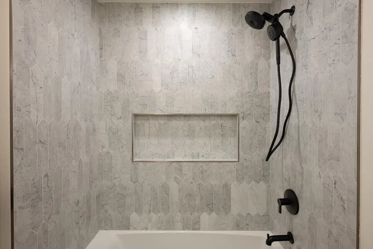 Tub and shower in stone-look tile with matte black fixtures