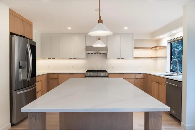 Oak kitchen with a large white island and a brass pendant