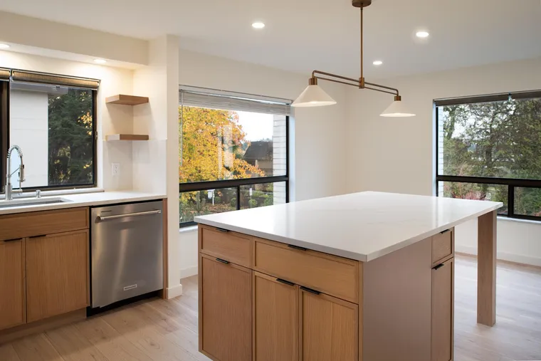 Oak island and white counters beside black-framed windows