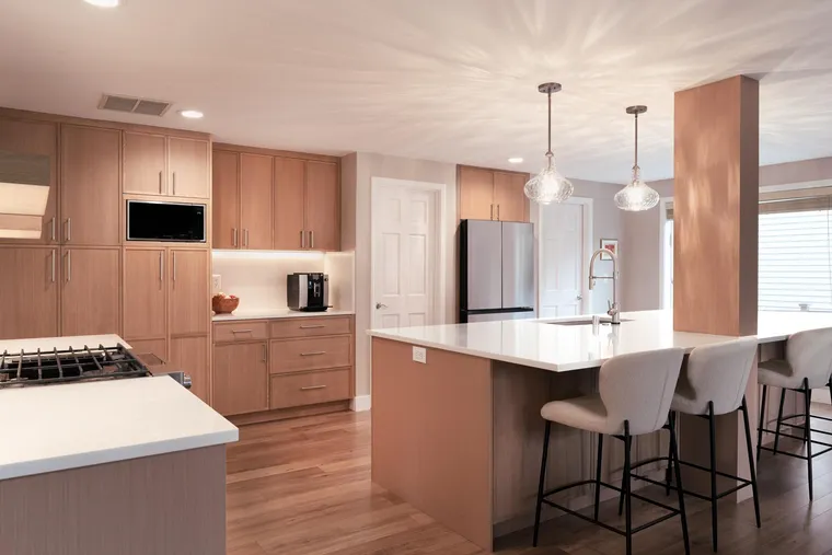Light oak kitchen with an island, counter stools and glass pendants