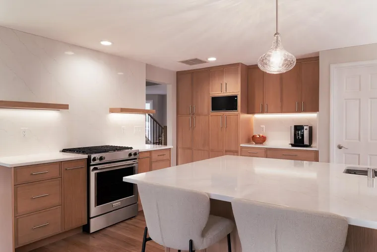 Light oak cabinetry and a white island with stools