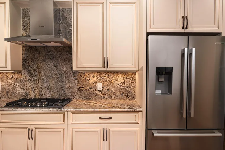 Cream cabinets, a granite backsplash and a stainless refrigerator