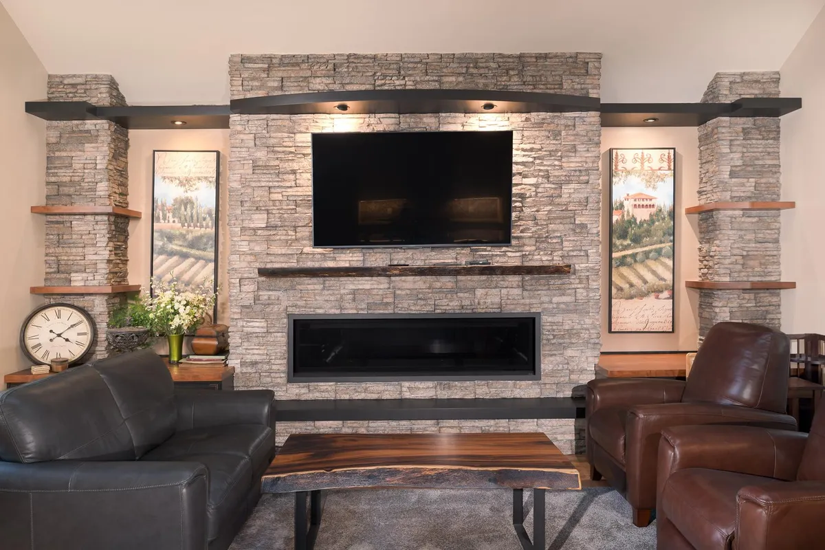 Living room with a stacked stone fireplace wall and floating shelves