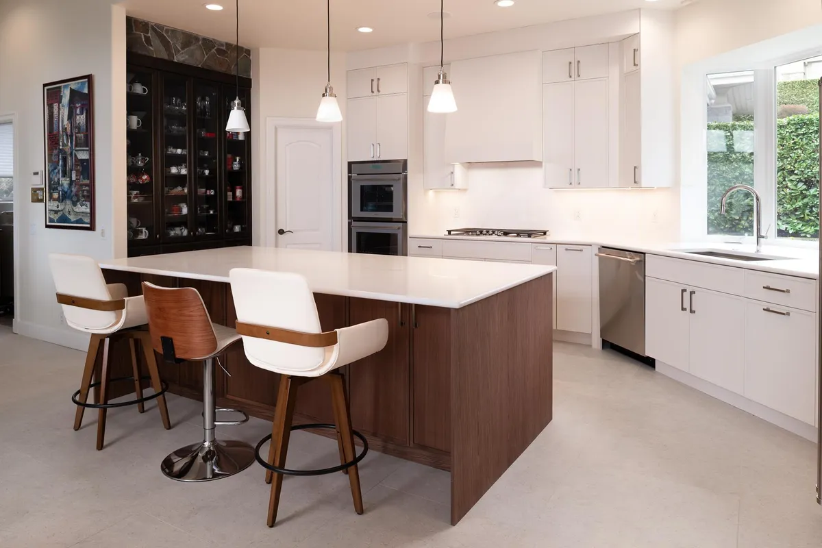Walnut island and white cabinets beside a glass-front wine wall