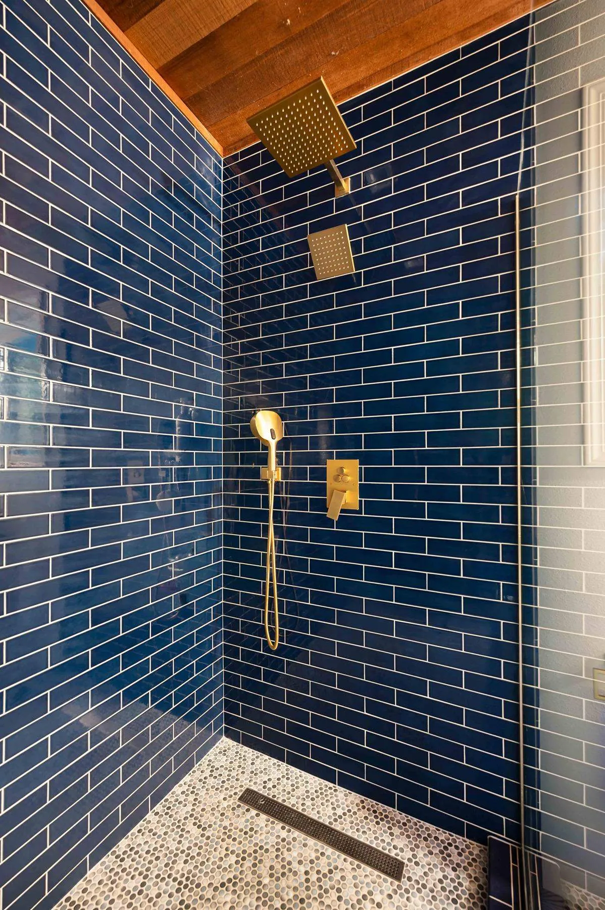 Brass shower fixtures against navy glazed tile