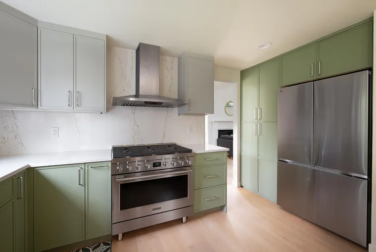 Sage green cabinetry with a stainless range and chimney hood