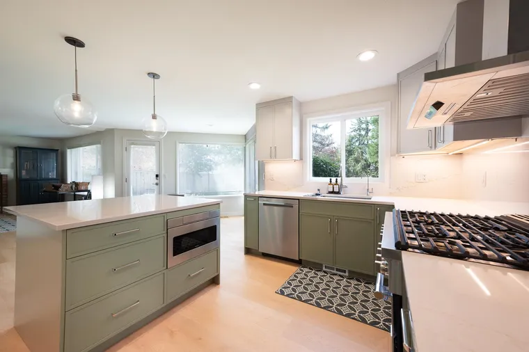 Sage green peninsula and white counters in an open kitchen