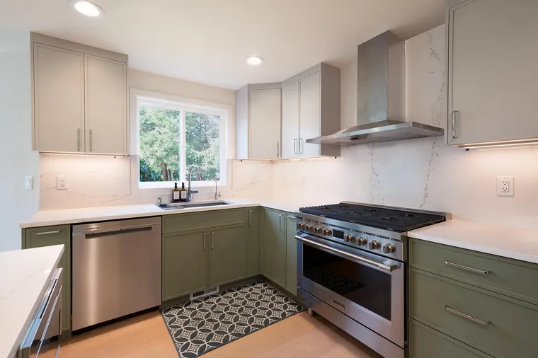 Sage lower cabinets, white uppers and a professional range