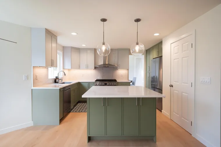 Sage kitchen with an island and glass pendant lights