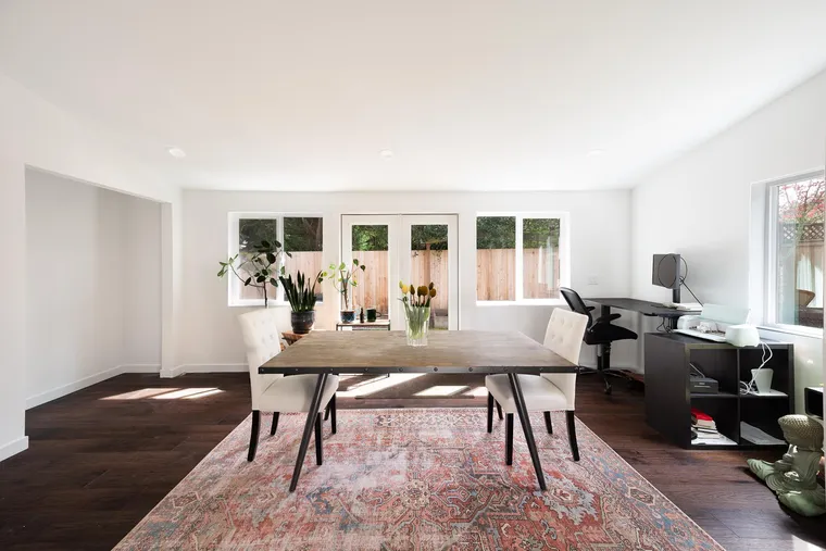 Bright new room with a dining table, a rug and windows on two sides