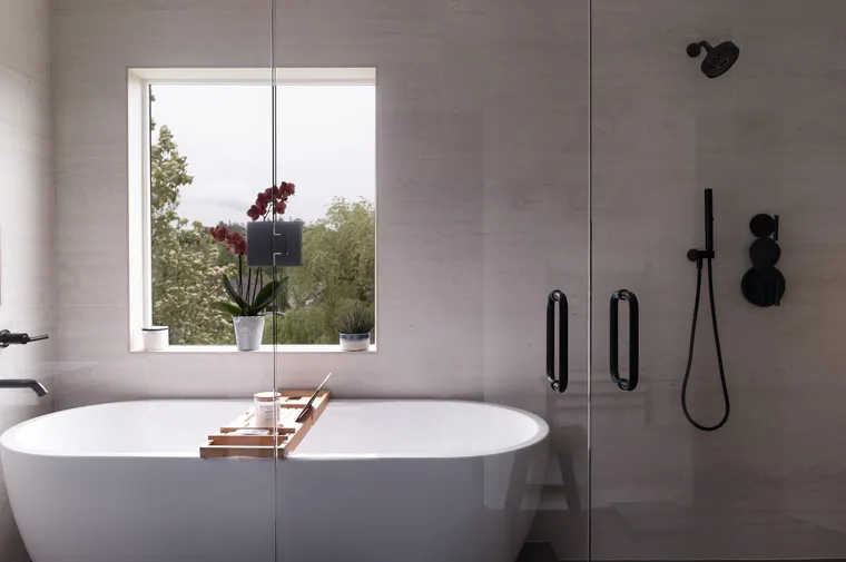 Freestanding tub and a glass shower in a gray primary bath