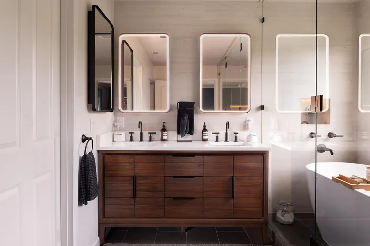 Walnut double vanity with black fixtures and rounded mirrors
