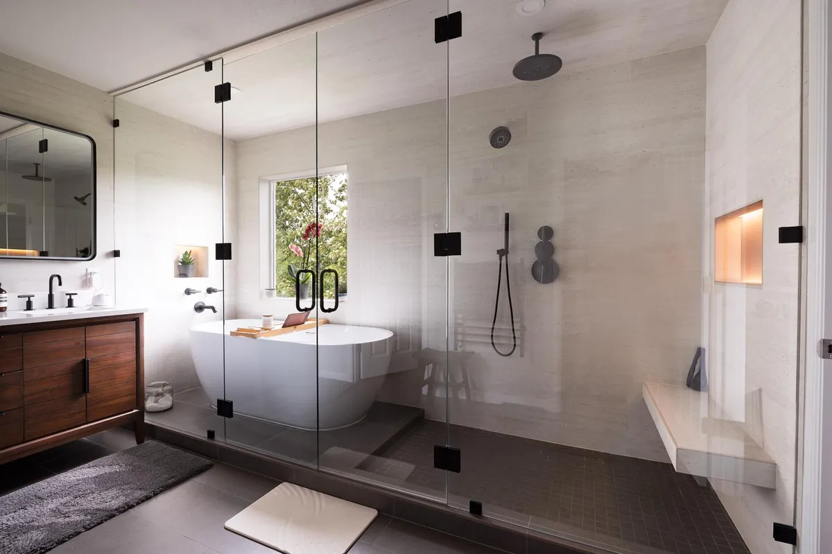 Primary bath with a walnut vanity, a glass shower and a freestanding tub under a garden window in Kenmore