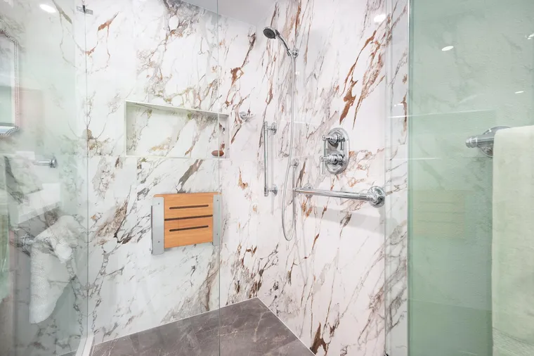 Marble-look shower with a fold-down teak seat and grab bars