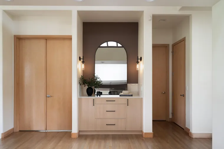 White oak entry doors and a built-in console under an arched mirror
