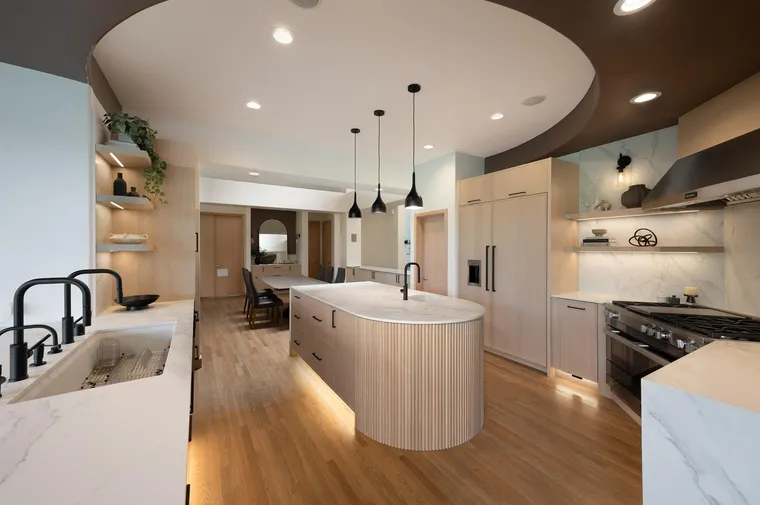 Open kitchen with a curved island and black pendant lights